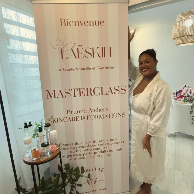 Laëty en peignoir blanc à côté de la bannière « Bienvenue, LaëSkin Masterclass »
