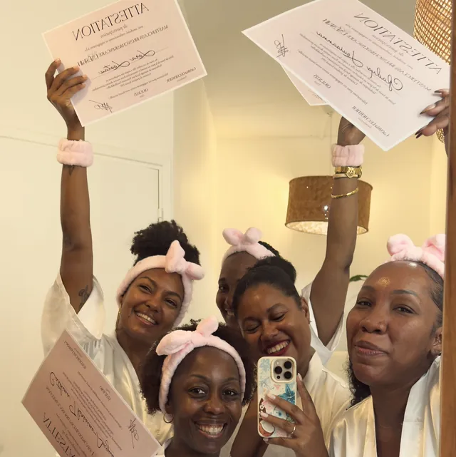 Des participantes souriantes, en bandeau rose, brandissent leur attestation