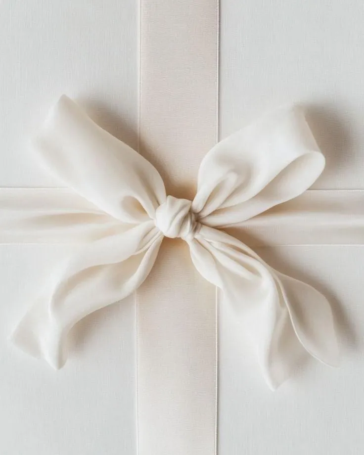 Un ruban de satin crème noué sur un coffret blanc
