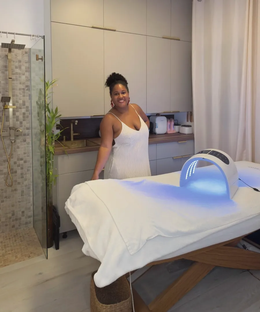 Laëtitia sourit dans sa cabine de soins, près de la table et du masque LED allumé en bleu