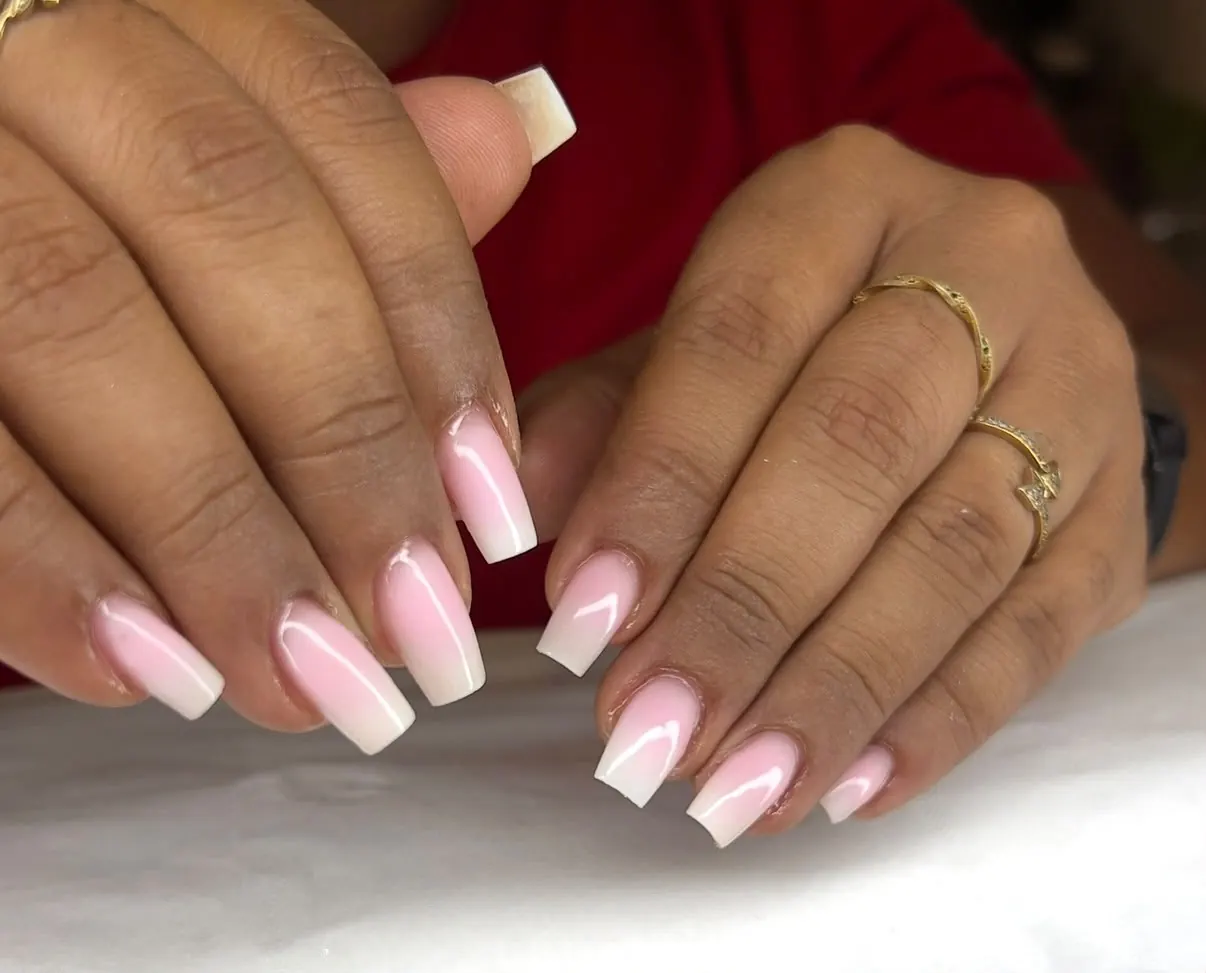 Une pose en baby boomer, du rose au blanc, sur des ongles carrés, bagues dorées aux doigts